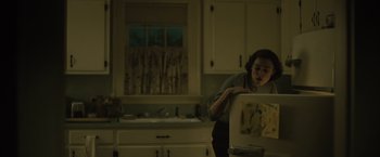 Movie still from “Boston Strangler” (2023), directed by Matt Ruskin – A woman standing in a kitchen next to an open window; Medium shot, High angle