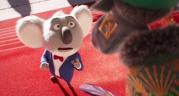 Movie still from “Sing 2” (2021), directed by Christophe Lourdelet – A koala is standing on a red carpet and looking at a cat; Close Up shot, Over the shoulder angle