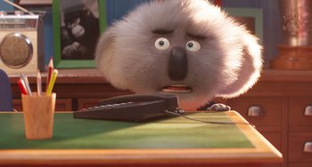 Movie still from “Sing 2” (2021), directed by Christophe Lourdelet – A furry animal is sitting next to a remote control; Close Up shot, Over the shoulder angle
