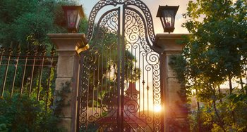Movie still from “Sing 2” (2021), directed by Christophe Lourdelet – A wrought - iron gate is open at the sunset; Extreme Wide shot, Low angle