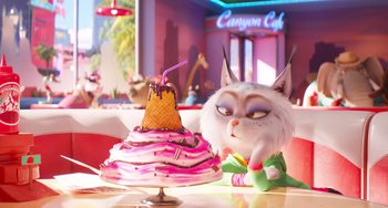 Movie still from “Sing 2” (2021), directed by Christophe Lourdelet – A cat sitting in front of a cake on top of a table; Medium shot, Over the shoulder angle