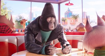 Movie still from “Sing 2” (2021), directed by Christophe Lourdelet – An animated gorilla sitting at a table in a restaurant; Medium shot, Over the shoulder angle