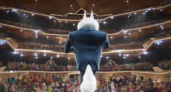Movie still from “Sing 2” (2021), directed by Christophe Lourdelet – A man in a suit and a white hat standing in front of an audience; Wide shot, Low angle