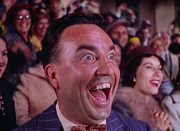 Movie still from “Singin' in the Rain” (1952), directed by Gene Kelly – A man in a crowd of people with his mouth wide open; Close Up shot, Low angle