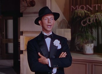 Movie still from “Singin' in the Rain” (1952), directed by Gene Kelly – A man in a suit and hat standing with his arms crossed; Medium shot, High angle
