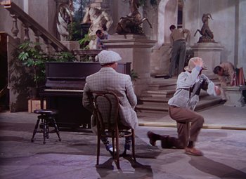 Movie still from “Singin' in the Rain” (1952), directed by Gene Kelly – Two men sitting in chairs in front of a grand piano; Wide shot, High angle