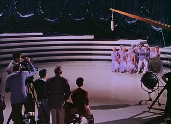 Movie still from “Singin' in the Rain” (1952), directed by Gene Kelly – A group of people standing in front of a stage; Wide shot, High angle