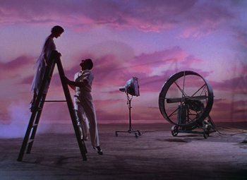Movie still from “Singin' in the Rain” (1952), directed by Gene Kelly – A man standing next to a woman on a ladder; Wide shot, Low angle