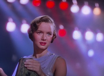 Movie still from “Singin' in the Rain” (1952), directed by Gene Kelly – A woman in a silver dress holding a purse; Medium shot, Low angle