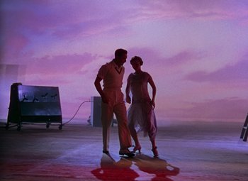 Movie still from “Singin' in the Rain” (1952), directed by Gene Kelly – A couple of people standing next to each other on a beach; Wide shot, Low angle