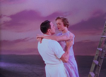 Movie still from “Singin' in the Rain” (1952), directed by Gene Kelly – A man and a woman embracing in front of the ocean; Wide shot, Low angle
