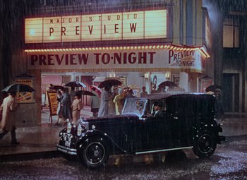 Movie still from “Singin' in the Rain” (1952), directed by Gene Kelly – An old car parked in front of a movie theater; Extreme Wide shot, High angle