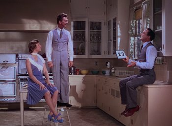 Movie still from “Singin' in the Rain” (1952), directed by Gene Kelly – Two men and a woman in a kitchen; Wide shot, Low angle