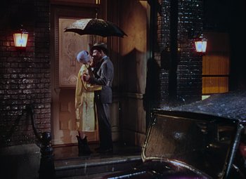 Movie still from “Singin' in the Rain” (1952), directed by Gene Kelly – A man and a woman standing under an umbrella; Wide shot, High angle
