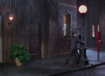 Movie still from “Singin' in the Rain” (1952), directed by Gene Kelly – A man in a business suit is standing next to a street light; Wide shot, Low angle