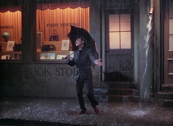Movie still from “Singin' in the Rain” (1952), directed by Gene Kelly – A man holding an umbrella while standing in the rain; Wide shot, High angle