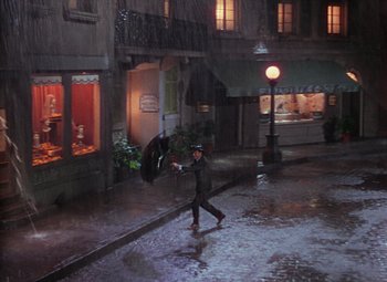 Movie still from “Singin' in the Rain” (1952), directed by Gene Kelly – A man walking down a street holding an umbrella; Extreme Wide shot, High angle