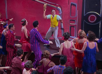 Movie still from “Singin' in the Rain” (1952), directed by Gene Kelly – A group of people in a room with a man holding a baseball glove; Wide shot, High angle