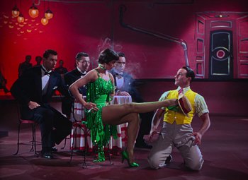 Movie still from “Singin' in the Rain” (1952), directed by Gene Kelly – A man kneeling down next to a woman in a green dress; Wide shot, Low angle