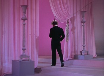 Movie still from “Singin' in the Rain” (1952), directed by Gene Kelly – A man in a suit standing in front of a pink wall; Wide shot, Low angle