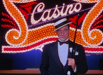 Movie still from “Singin' in the Rain” (1952), directed by Gene Kelly – A man in a tuxedo holding a cane in front of a neon sign; Medium shot, Low angle