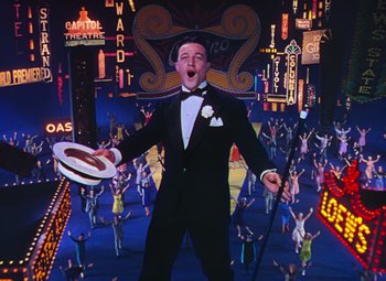 Movie still from “Singin' in the Rain” (1952), directed by Gene Kelly – A man wearing a tuxedo and holding a hat in his hand; Wide shot, Low angle