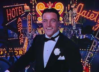Movie still from “Singin' in the Rain” (1952), directed by Gene Kelly – A man in a tuxedo standing in front of neon lights; Medium shot, Low angle
