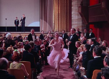 Movie still from “Singin' in the Rain” (1952), directed by Gene Kelly – A woman in a pink dress is walking down the aisle; Wide shot, High angle
