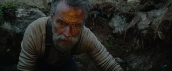 Movie still from “Sisu” (2022), directed by Jalmari Helander – An old man with a long gray beard is looking at the camera; Close Up shot, High angle