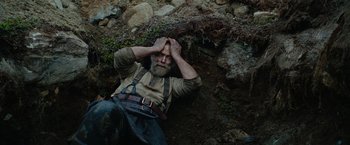 Movie still from “Sisu” (2022), directed by Jalmari Helander – An old man laying on the ground with his hands on his head; Medium shot, Overhead angle