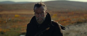 Movie still from “Sisu” (2022), directed by Jalmari Helander – An old man with a beard and a long mustache; Medium shot, Low angle