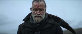 Movie still from “Sisu” (2022), directed by Jalmari Helander – A person wearing a coat; Close Up shot, Low angle