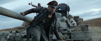 Movie still from “Sisu” (2022), directed by Jalmari Helander – A man in a leather jacket and a hat; Medium shot, Low angle
