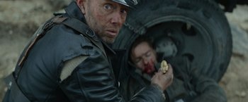Movie still from “Sisu” (2022), directed by Jalmari Helander – A man eating a piece of food next to another man; Close Up shot, Over the shoulder angle