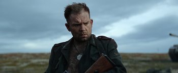 Movie still from “Sisu” (2022), directed by Jalmari Helander – A person holding a gun; Close Up shot, Low angle