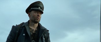 Movie still from “Sisu” (2022), directed by Jalmari Helander – A man wearing a leather jacket and a hat; Close Up shot, Low angle