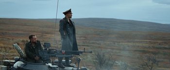 Movie still from “Sisu” (2022), directed by Jalmari Helander – A man in a military uniform standing on top of a hill; Wide shot, Low angle