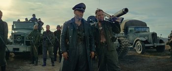 Movie still from “Sisu” (2022), directed by Jalmari Helander – A couple of men standing next to each other on top of a field; Medium shot, Low angle