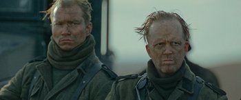 Movie still from “Sisu” (2022), directed by Jalmari Helander – Two men in military fatigues are looking at the camera; Close Up shot, Over the shoulder angle