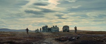 Movie still from “Sisu” (2022), directed by Jalmari Helander – A group of people standing next to an army vehicle; Extreme Wide shot, Low angle