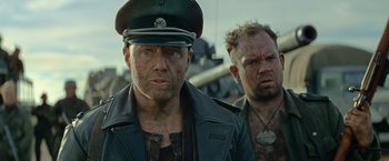 Movie still from “Sisu” (2022), directed by Jalmari Helander – A man in a military uniform next to another man in a leather jacket; Close Up shot, Low angle