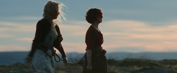 Movie still from “Sisu” (2022), directed by Jalmari Helander – A woman holding onto a rope while standing next to another woman; Wide shot, Low angle