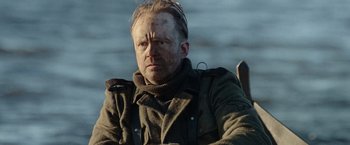 Movie still from “Sisu” (2022), directed by Jalmari Helander – A man in a military jacket sitting in a chair; Close Up shot, Over the shoulder angle