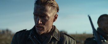 Movie still from “Sisu” (2022), directed by Jalmari Helander – A person wearing a military uniform; Close Up shot, Over the shoulder angle