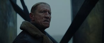 Movie still from “Sisu” (2022), directed by Jalmari Helander – An older man with a beard and a mustache; Close Up shot, Low angle