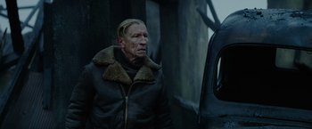 Movie still from “Sisu” (2022), directed by Jalmari Helander – An older man wearing a leather jacket and fur collar; Close Up shot, Over the shoulder angle
