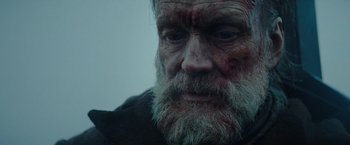 Movie still from “Sisu” (2022), directed by Jalmari Helander – An old man with a beard is looking into the distance; Close Up shot, Low angle