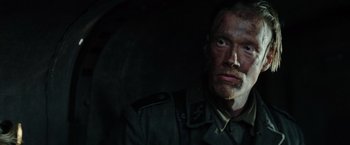 Movie still from “Sisu” (2022), directed by Jalmari Helander – A man in a military uniform looking at the camera; Close Up shot, Low angle