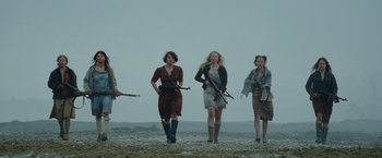 Movie still from “Sisu” (2022), directed by Jalmari Helander – A group of women walking across a beach holding guns; Wide shot, Low angle