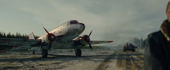 Movie still from “Sisu” (2022), directed by Jalmari Helander – An airplane is sitting on a runway in the middle of the day; Extreme Wide shot, Low angle
